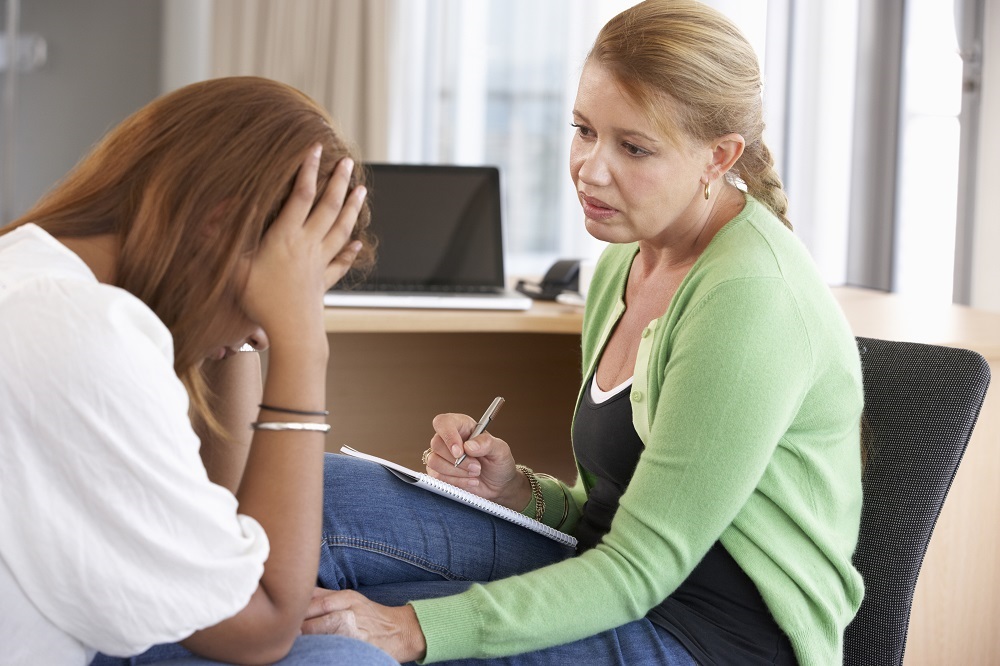 Counselor listens to distressed woman in office.
