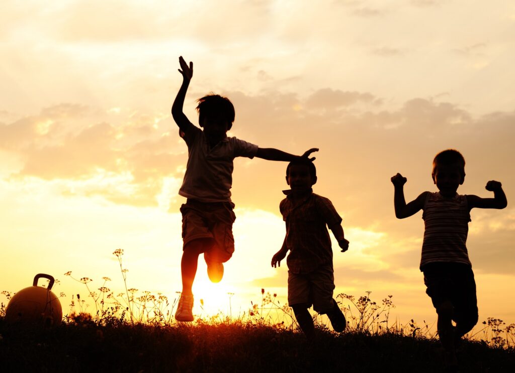 Children playing in sunset silhouette scene.