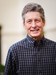 Smiling man in checkered shirt outdoors.